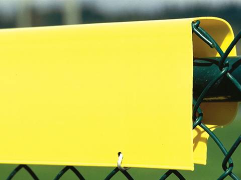 Yellow fence topper covers on the top of chain link fence.